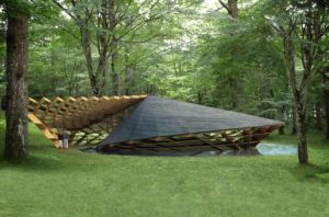 A modern architectural structure with a geometric, angular design covered in wooden and slate materials is situated in a forested area, blending with the surrounding trees and greenery. Two people are standing near the structure's entrance, marveling at the impressive architecture. - a room in the garden