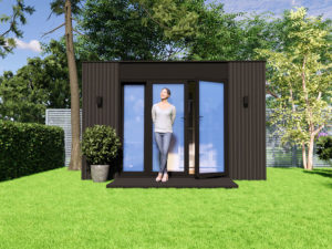 A woman stands smiling at the entrance of a modern, dark-colored garden cabin with open glass doors. The cabin is situated on a lush green lawn, surrounded by trees and plants, creating a serene backyard setting on a sunny day. - a room in the garden