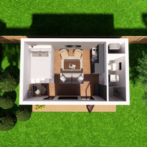 Top-down view of a small, modern studio apartment with a bed, two armchairs around a coffee table, and a wall-mounted TV. The liveable space includes a kitchenette and bathroom. The apartment opens to a wooden deck surrounded by lush green grass and a few bushes. - a room in the garden